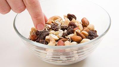 Young woman picking at a bowl of nuts